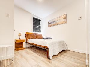 ein weißes Schlafzimmer mit einem Bett und einem Fenster in der Unterkunft Griffintown Hideout in Montreal