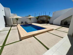 a house with a swimming pool and two umbrellas at Casa Flamingo, San Carlos in San Carlos