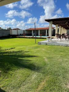 a green yard with two chairs and a pavilion at Casa de praia Morro Branco in Beberibe