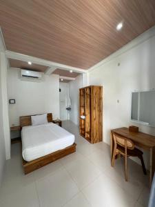 a bedroom with a bed and a desk and a television at La Casa de Maria in Komodo Labuan Bajo Airport