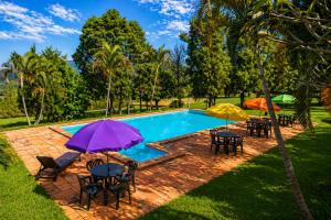 a pool with tables and chairs and umbrellas at Sopro do Vento Roots Hotel in Analândia +6 photos