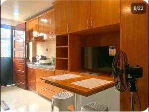 a kitchen with wooden cabinets and a large television at Studio Apartment in Mactan, Cebu Room304 in Lapu Lapu City