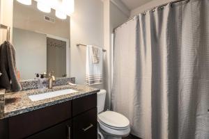 a bathroom with a toilet and a shower curtain at The West End Flats Hotel in Roanoke +1 photo