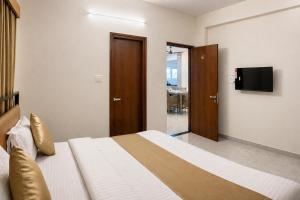 ein Schlafzimmer mit Bett und Flachbildfernseher in der Unterkunft DeVerveil Service Apartment in Mysore