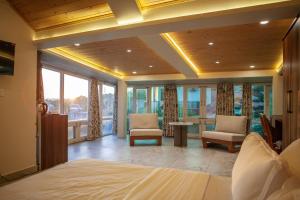 a bedroom with a bed and chairs and windows at Ruscello in Pālampur