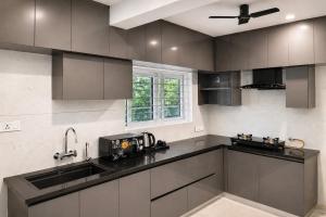 eine Küche mit grauen Schränken, einer Spüle und einem Fenster in der Unterkunft DeVerveil Service Apartment in Mysore