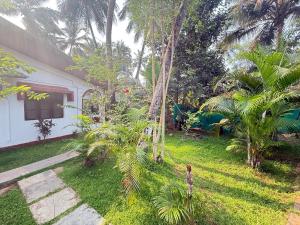 a yard with palm trees and a house at RnB Beach Resort in Anjuna