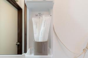 a white container with toothbrushes in it next to a mirror at Coto House Kamakura RoomB in Kamakura +66 photos
