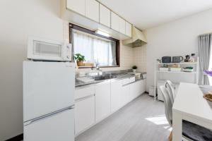 a kitchen with white cabinets and a microwave at Coto House Kamakura RoomB in Kamakura