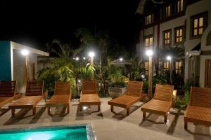 um grupo de cadeiras sentadas ao lado de uma piscina à noite em Pousada Castello Montemare em Ubatuba
