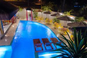 una piscina con sillas, mesas y sombrillas en Pousada Castello Montemare, en Ubatuba