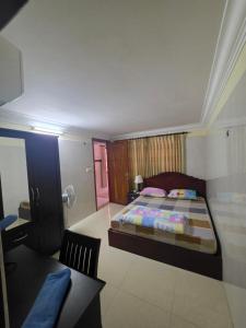 a bedroom with a bed and a desk and a table at Toul Sleng Double Room in Phnom Penh