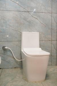 a white toilet with a hose attached to a wall at HOTEL AIKAA in Hyderabad +60 photos