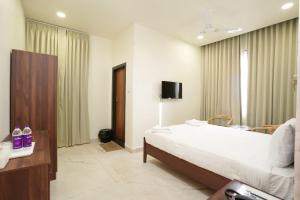 a hotel room with a bed and a tv at HOTEL AIKAA in Hyderabad