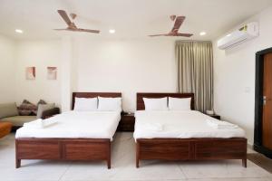 a bedroom with two beds and a couch at HOTEL AIKAA in Hyderabad