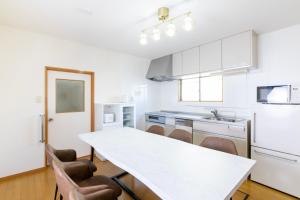 a white kitchen with a white table and chairs at gently stay Nagoya in Nagoya +32 photos
