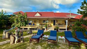 a house with blue and white chairs in the yard at Sunset Cove Villa in Grand'Anse Praslin
