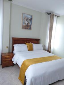 a bedroom with a large bed with white sheets and yellow pillows at Keirwa in Kampala
