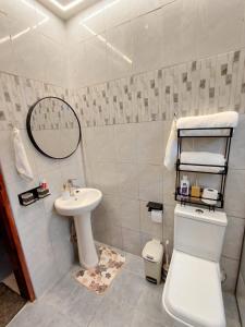 a white bathroom with a sink and a toilet at Keirwa in Kampala