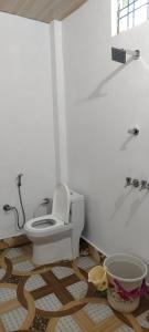 a white bathroom with a toilet and a shower at DJSR Resort in Barkot