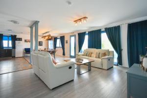a living room with white furniture and blue curtains at Pike Inn Bucătărie Autentică & Cazare cu Farmec in Dunavăţu de Sus