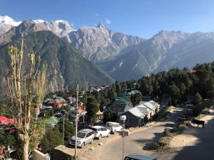 a small town with cars parked in front of mountains at Aangan by Mom in Kalpa