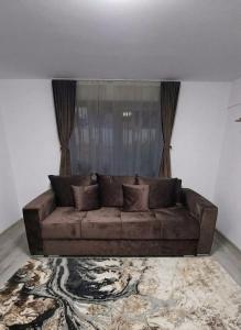 a brown couch in a living room with a window at Casa Vatra Dornei in Vatra Dornei