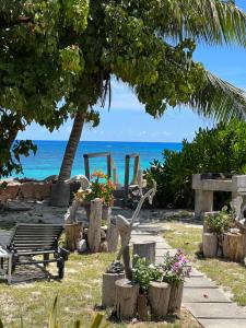 a park with a bench and flowers and the ocean at Sunset Cove Villa in Grand'Anse Praslin