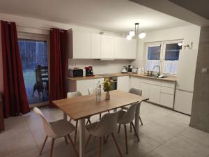 a kitchen with a wooden table and chairs in a kitchen at Lisia Górka in Debina +9 photos