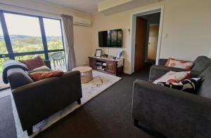 a living room with two couches and a large window at 2-bedroom harbour view apartment with parking, 8 mins to Dunedin in Dunedin