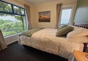 a bedroom with a bed and a large window at 2-bedroom harbour view apartment with parking, 8 mins to Dunedin in Dunedin