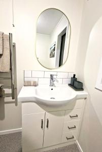 a bathroom with a white sink and a mirror at 2-bedroom harbour view apartment with parking, 8 mins to Dunedin in Dunedin +10 photos
