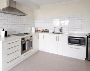 a kitchen with white cabinets and a sink at 2-bedroom harbour view apartment with parking, 8 mins to Dunedin in Dunedin