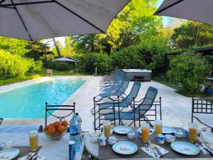Ein Tisch mit Stühlen und einem Sonnenschirm neben einem Pool in der Unterkunft Domaine de Ris in Ris-Orangis