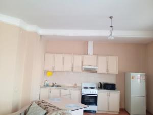 a small kitchen with white cabinets and a white refrigerator at Абай2 103 in Astana