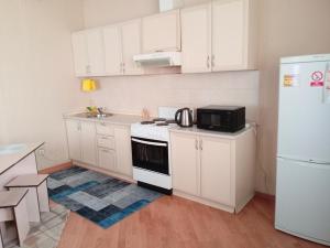 a kitchen with white cabinets and a stove and a refrigerator at Абай2 103 in Astana