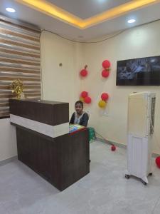 a woman sitting at a counter in a room with balloons at Hotel Galaxy in Mundarwa