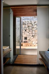 a bathroom with a stone wall behind a glass door at TULUM Beachfront Villa Kiin in Tulum