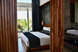 a bedroom with a bed and a bathroom with a sink at TULUM Beachfront Villa Kiin in Tulum