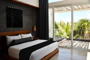 a bedroom with a bed and a large window at TULUM Beachfront Villa Kiin in Tulum