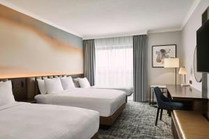 a hotel room with two beds and a desk at London Marriott Hotel Marble Arch in London