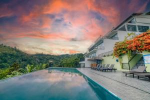 a pool at a resort with a sunset in the sky at The Pinnacle Ella Boutique Hotel and Spa in Ella