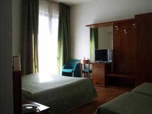a hotel room with two beds and a television at Hotel Traghetto in Civitavecchia
