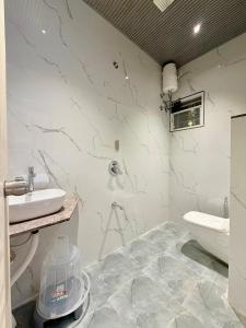 a white bathroom with a sink and a toilet at Saiprasad suite & stay in Ellora