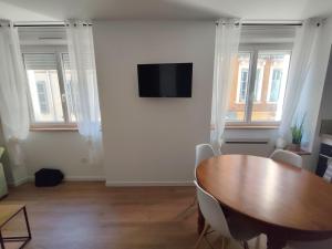 a dining room with a table and a flat screen tv at Appartement Centre in Lourdes