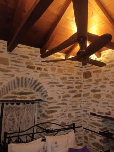 a ceiling fan in a room with a stone wall at Archontiko Michael Pelion in Vyzitsa