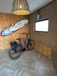 a bike parked in a room with a surfboard on the wall at Beachhouse Anna, 1 minute walk to the beach and centre of Katwijk, Free private parking next to the house ! in Katwijk aan Zee
