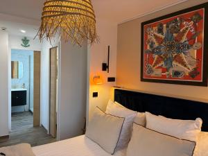 a bedroom with a bed and a painting on the wall at Hôtel Le Neptune en Camargue in Saintes-Maries-de-la-Mer