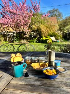 a picnic table with bread and fruit and a cup of coffee at Chambre du bout d'Auvers in Noisy-sur-École
