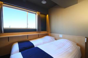 a small bedroom with a bed and a window at Hotel Wing International Select Asakusa Komagata in Tokyo